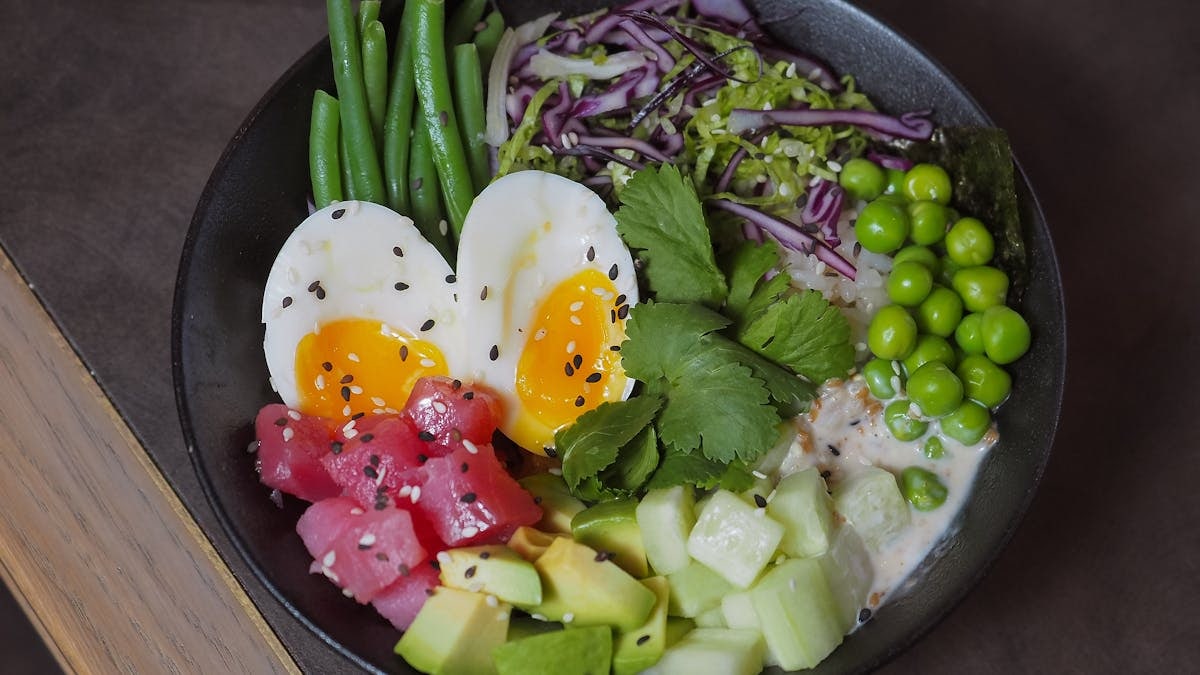 A delicious and colorful poke bowl featuring eggs, vegetables, and fresh produce, perfect for a healthy meal.
